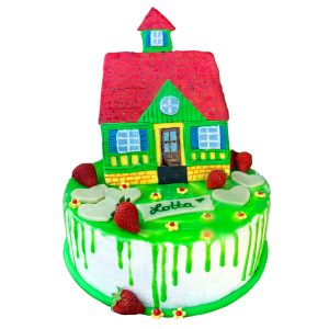 Torte mit modelliertem Haus auf grünem Rasen